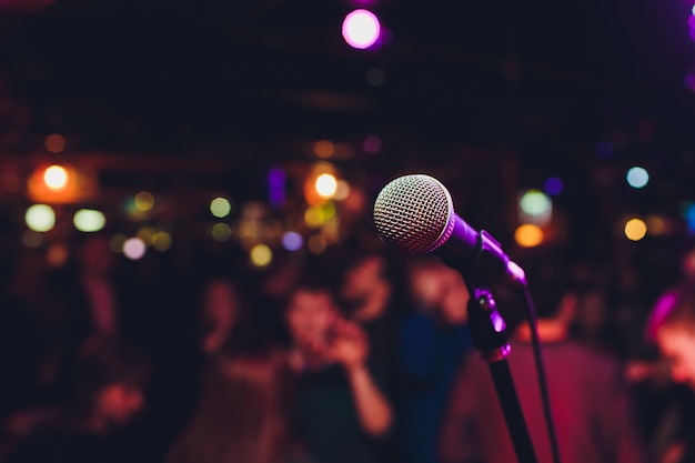 Photo microphone with blurred colorful bright light in dark night background, soft focus image for business technology communication concepts.