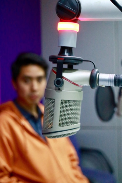 Microphone with man sitting in background at recording station