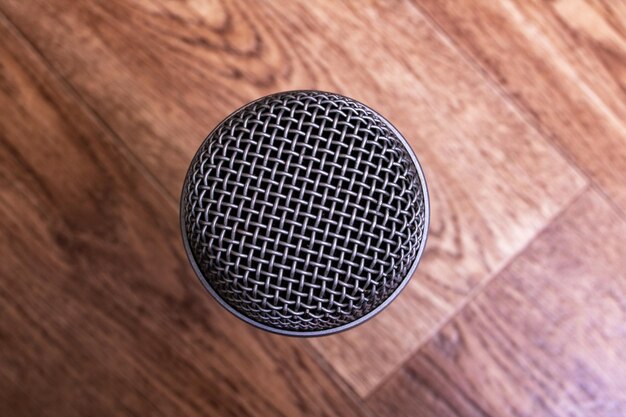 Microphone on wooden background top view closeup