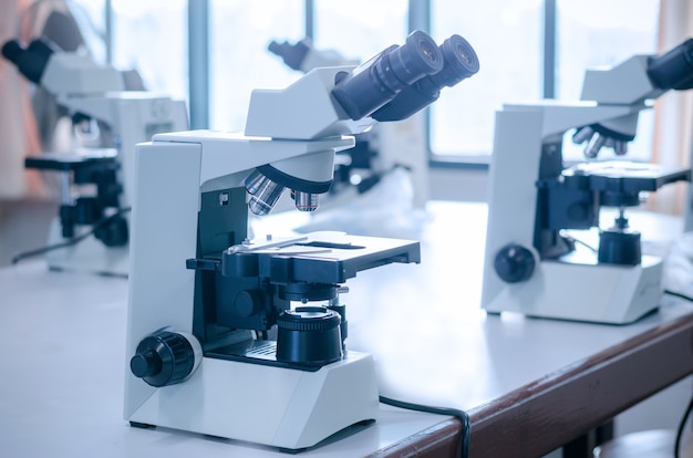 Microscoop met microplaat op witte lijst in laboratorium die voor onderzoek en het leren plaatsen