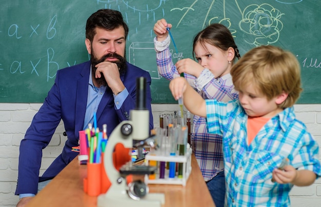 Strumento ottico microscopio in aula di scienze torna a scuola bambini felici insegnante impara usando il microscopio a lezione scolastica sviluppo precoce dei bambini bambini amichevoli in laboratorio