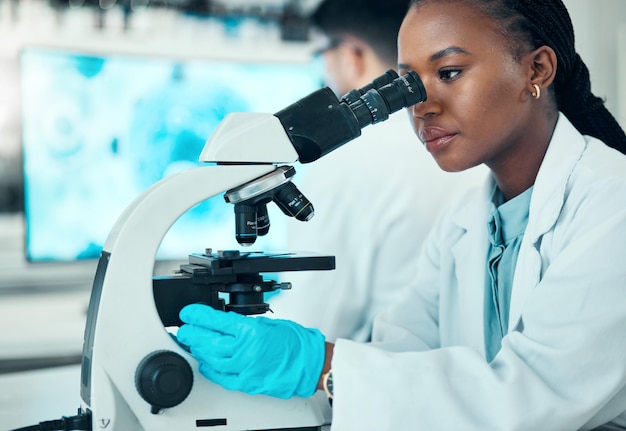 Microscope science and female scientist in a lab for medical pharmaceutical research Professional scientific and African woman researcher working on molecule analysis with biotechnology equipment