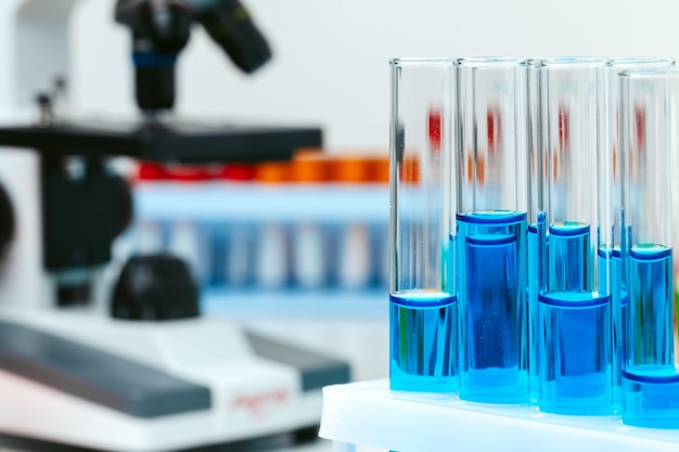 Microscope and test tubes on table in laboratory, close up