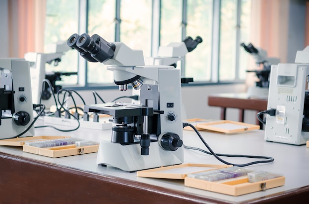 Foto microscopio con micropiastra sul tavolo bianco in ambiente di laboratorio per la ricerca e l'apprendimento