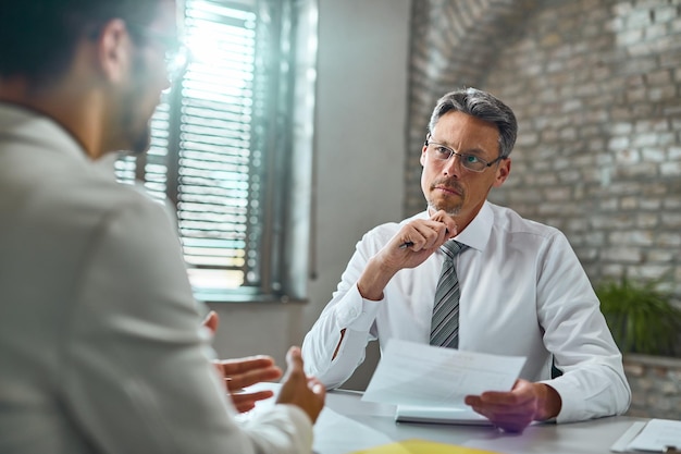 Mid adult businessman listening to a candidate during job interview in the office