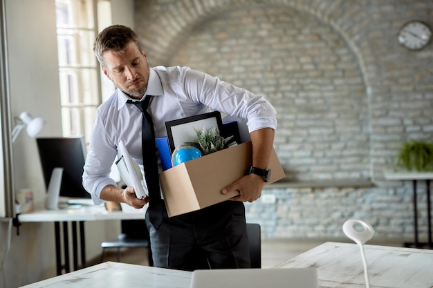 Mid adult businessman taking his belongings from the office after being fired