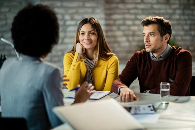 Mid adult couple talking to their financial advisor during a meeting in the office Focus is on happy woman