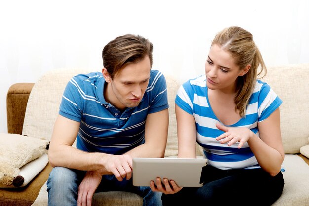 Foto mid adult couple zit met een digitale tablet op de bank in de woonkamer thuis