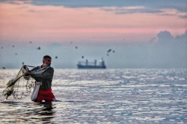 写真 夕暮れの海で釣りをしている中年男性