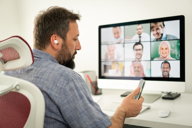 Mid adult man having online conference working from home