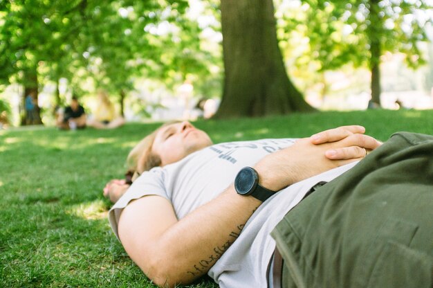 Foto uomo adulto a metà che giace sull'erba nel parco