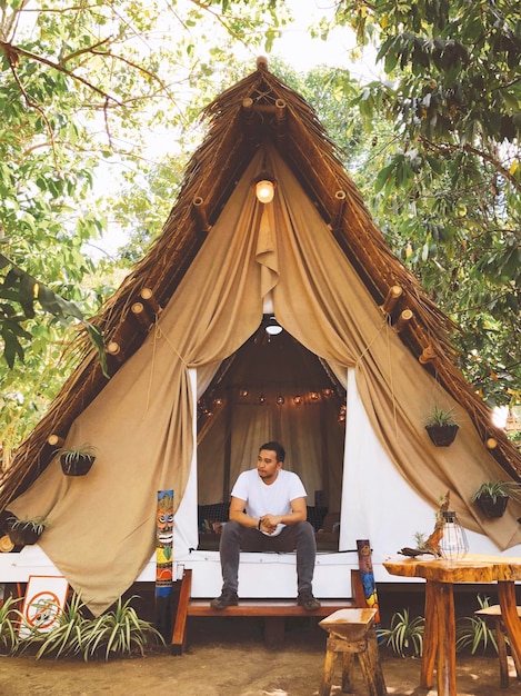 Foto uomo adulto a metà seduto all'ingresso di glamping