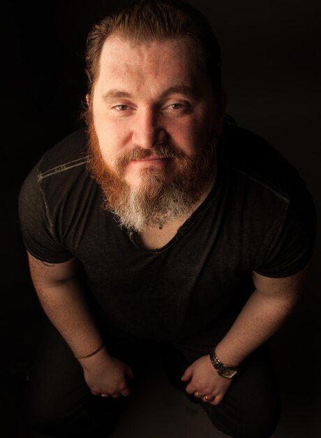 Mid adult man with beard against black background