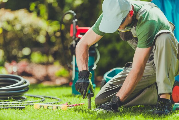 Photo mid adult man working on grassy field at yard