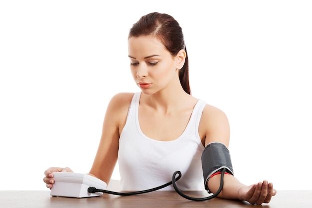 mid adult woman checking blood pressure on table against white background