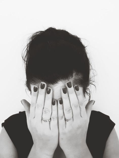 Photo mid adult woman covering face with hands against white background