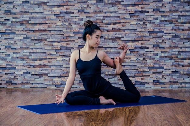 Photo mid adult woman doing yoga on hardwood floor