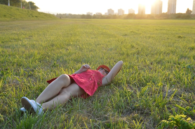 Photo mid adult woman lying on grassy field during sunset