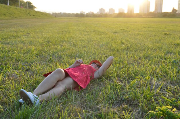 写真 夕暮れの草原に横たわっている中年女性