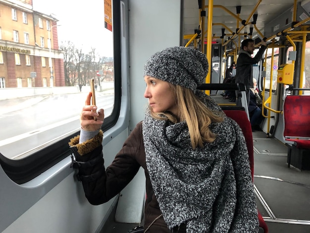 写真 バスで旅している中年女性が携帯電話で写真を撮っている