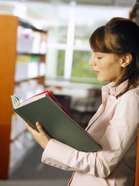 Foto donna adulta che legge un libro in biblioteca