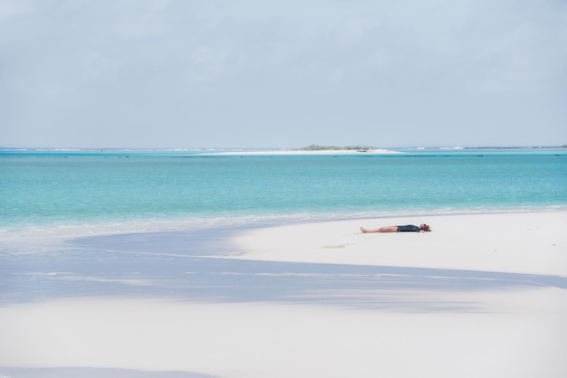 Photo mid adult woman relaxing on sand at beach against sky