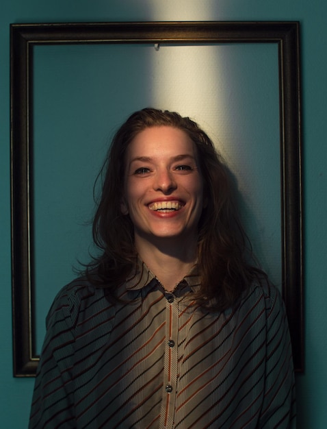 mid adult woman standing against picture frame on wall