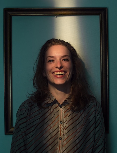 Photo mid adult woman standing against picture frame on wall