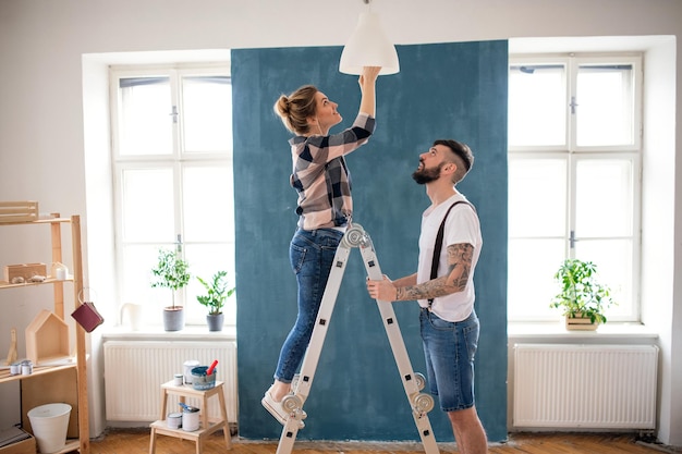 中年カップルが家の中で電球を交換する 移転とDIYコンセプト