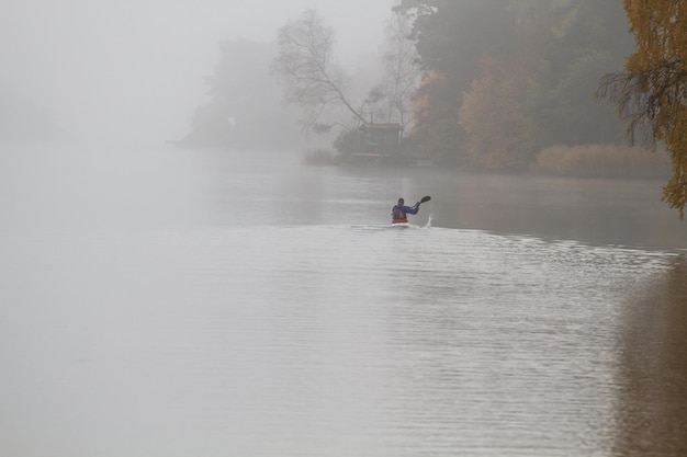 Foto mid-afstand uitzicht van persoon roeiende boot in het meer tijdens mistig weer