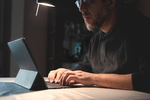 Бизнесмен средних лет использует планшет и интернет, работая из дома в условиях блокады из-за коронавируса