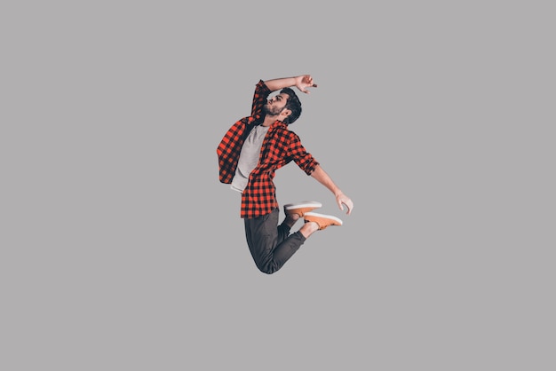 In mid-air. Mid-air shot of handsome young man jumping and gesturing against background