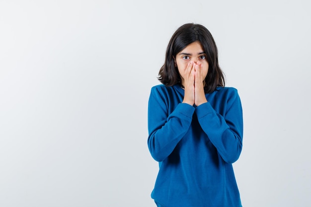 Mid cut hair teenager girl in blue sweater put hands over mouth and looking sadly isolated on white background