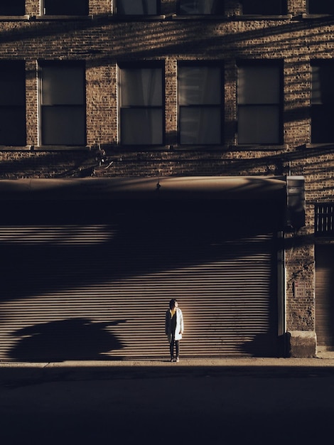 Фото Средний отдаленный вид женщины, стоящей на тротуаре против здания