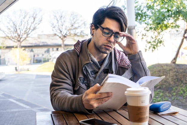 Colpo di media lunghezza di un uomo attraente seduto in un bar a bere caffè mentre legge un libro.