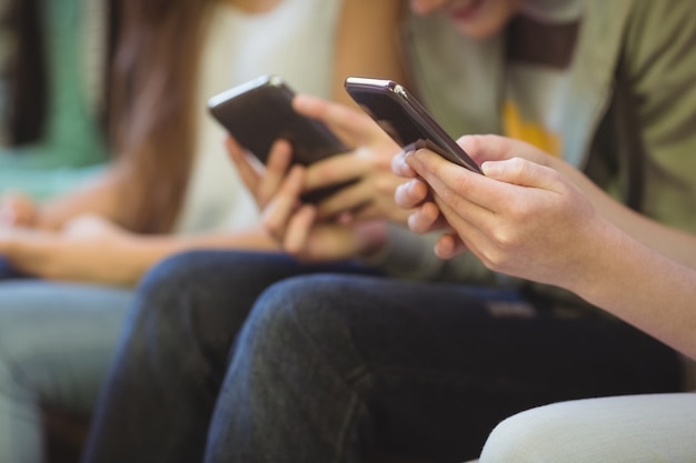 Mid sectie van schoolvrienden met behulp van mobiele telefoon