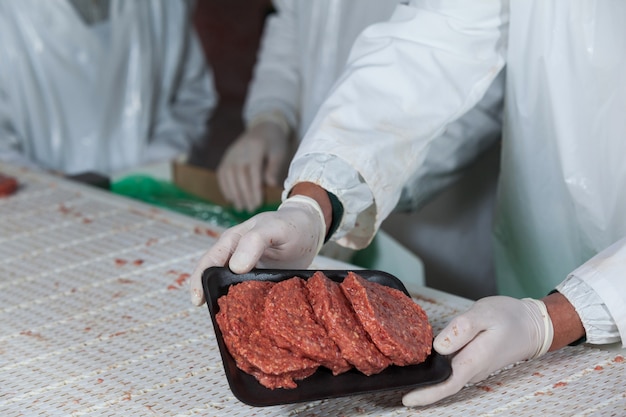 Mid sectie van slager met rauw vlees pasteitjes gerangschikt in lade