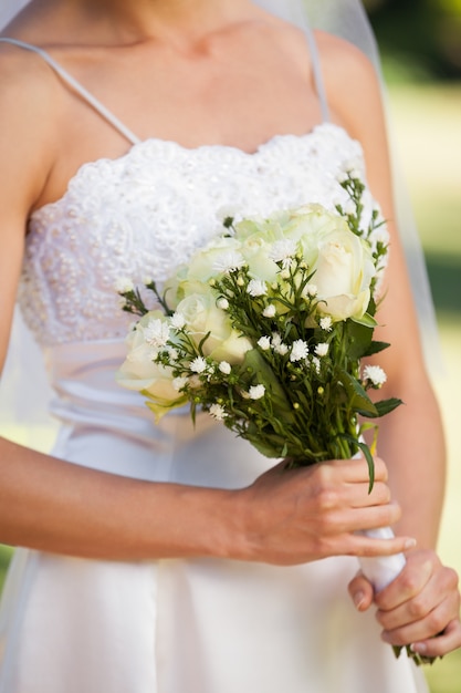 Mid section of a beautiful bride with bouquet in park