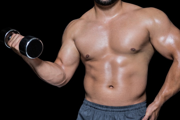 Mid section of a bodybuilder with dumbbell