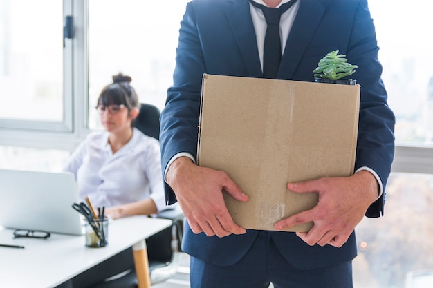 Mid section of businessman carrying cardboard box of stuff for new workplace