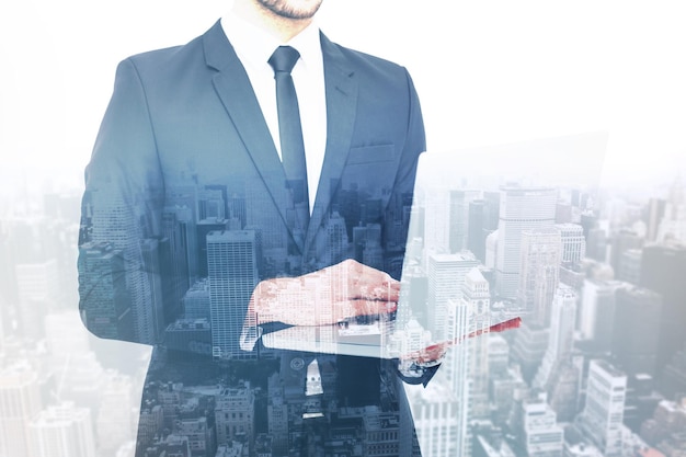 mid section of a businessman using laptop against high angle view of city