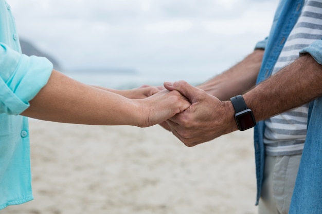 Mid section of couple holding hands on beach