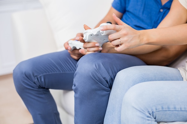 Mid section of couple playing video game 