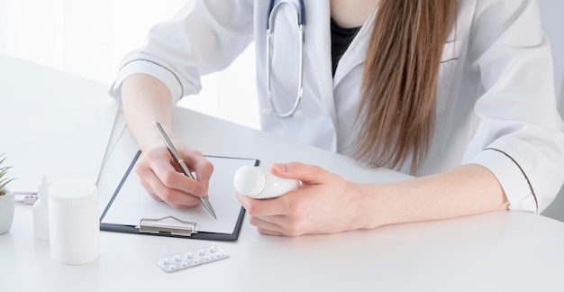 Mid section of female doctor writes prescription to patient at worktable Panacea and life save prescribing treatment