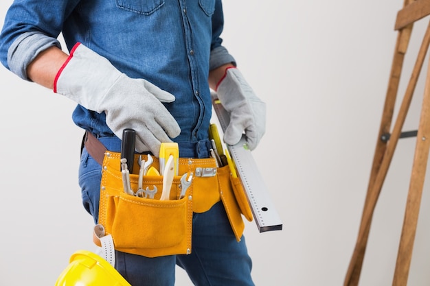 Photo mid section of a handyman with toolbelt and hard hat