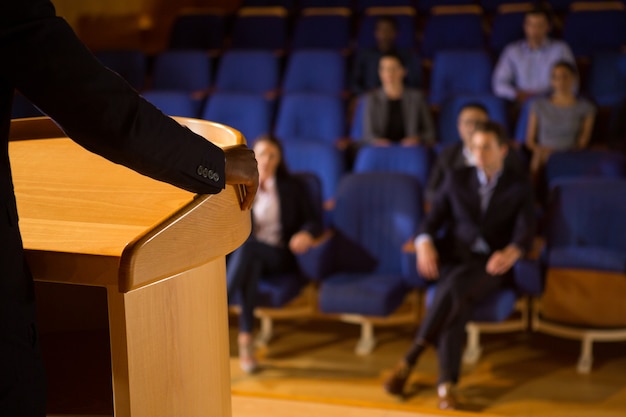 Mid section of male business executive giving a speech at conference center