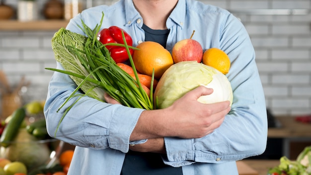 Photo mid-section of man holding raw vegetables at home