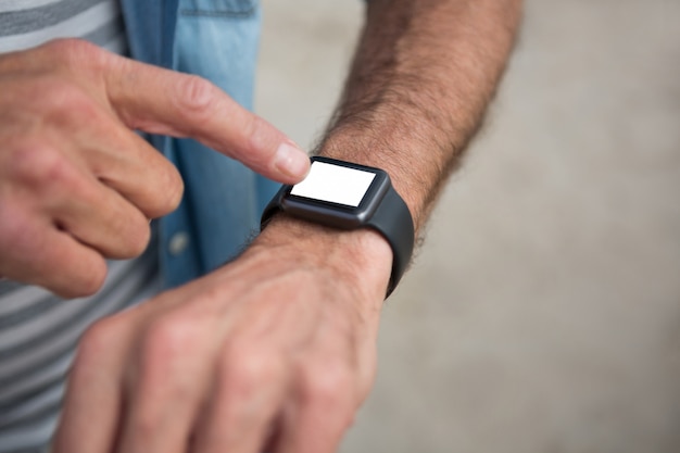 Mid section of man wearing smartwatch on beach