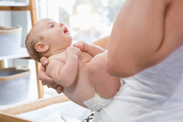 Mid-section of mother holding her baby boy