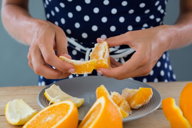 Фото Средняя часть женщины, очищающей апельсин